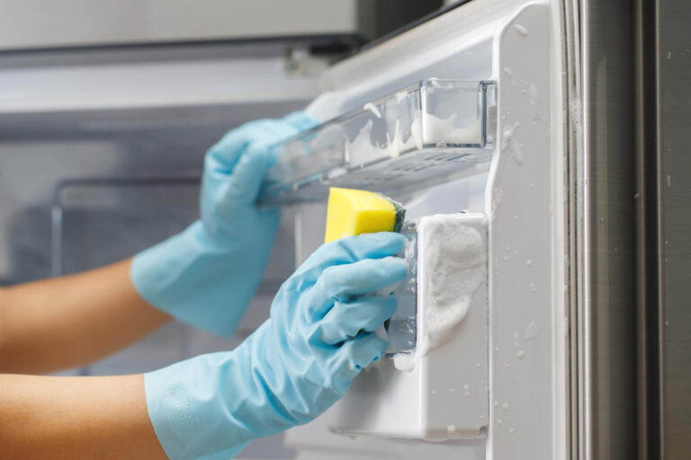 Bonnie's Cleaning worker scrubbing the inside of a refrigerator with a sponge. The best deep cleaning in Moose Jaw