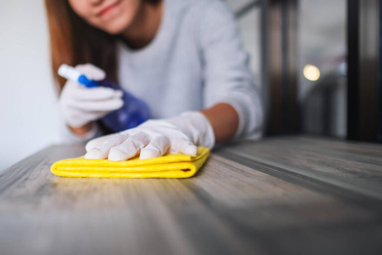 Woman with yellow glove cleaning a table. Apartment cleaning in Manhattan. Maid services in Brooklyn
