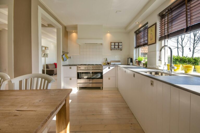 kitchen with a table, white chairs, and white cabinets underneath an open window. Maid services in Moose Jaw. House cleaning in Brooklyn. Woodside